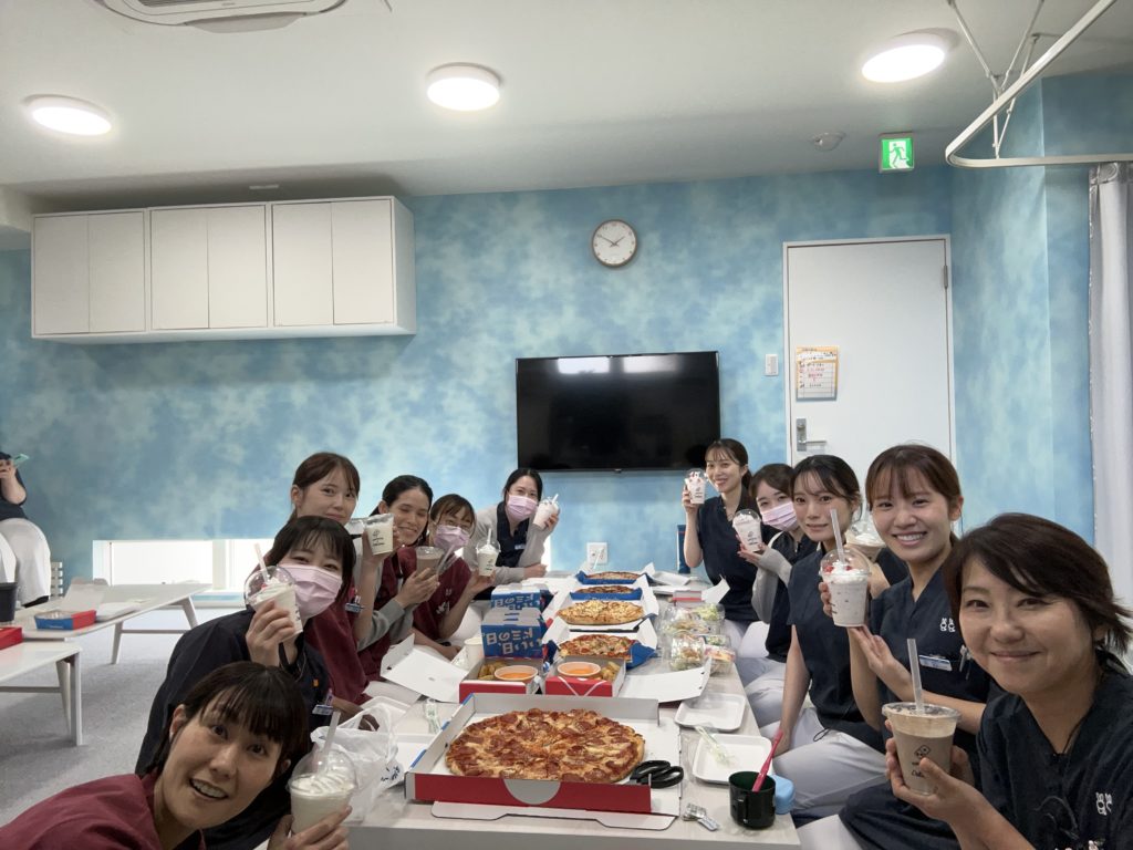 休憩室でピザとドリンクを囲むかけまちコミュニティー歯科のスタッフ